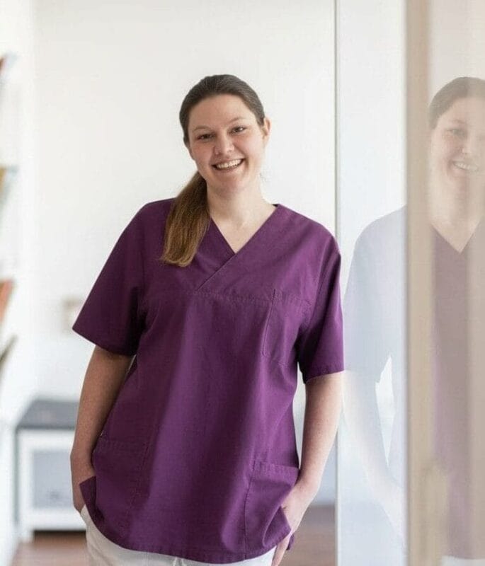 Nicole Rübbelke, Mitarbeiterin des Praxisteams der gastroenterologischen Praxis Dr. med. Stockhammer, an eine Glaswand gelehnt.